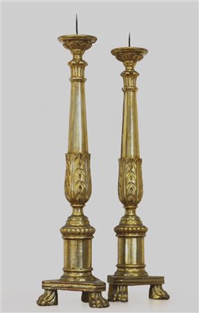 Coppia di candelieri tripodi in legno intagliato e dorato a motivi vegetali, se