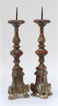 Coppia di candelieri in legno intagliato e laccato con tracce di doratura a mec