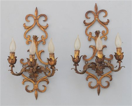 Coppia di appliques a tre luci in metallo dorato a volute e motivi fogliati (cm