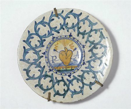 Piatto in maiolica con al centro "curoe trafitto e iniziali" tesa con...