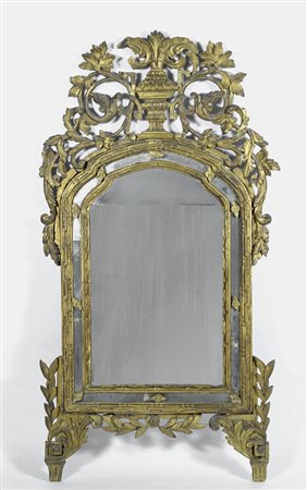 Specchiera in noce intagliata e dorata, ampia cimasa con urna affiancata da...