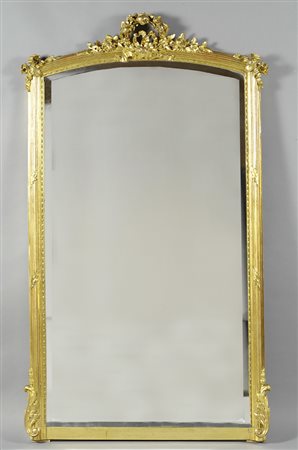 Specchiera in legno dorato, con cornice scanalata, cimasa intagliata con...