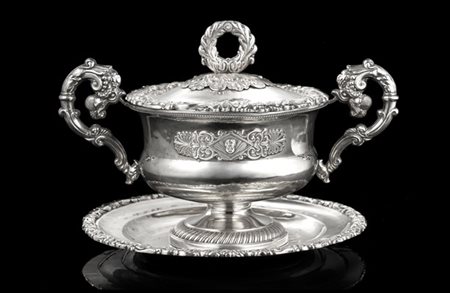 Zuccheriera biansata con piattino in argento. Bordi decorati a volute fogliate,