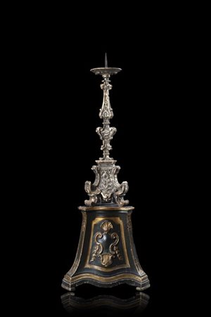 Candeliere in legno intagliato e argentato a volute fogliate, poggiante su base