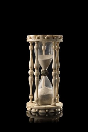 Manifattura del secolo XIX. Clessidra in avorio con basi scolpite a fiori e col