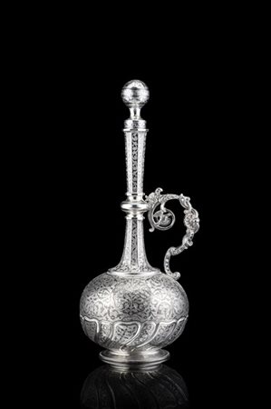 Bottiglia in argento niellato inciso e cesellato a volute fogliate. Ansa a volu