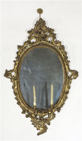Specchiera di forma ovale con cornice riccamente intagliata, con...