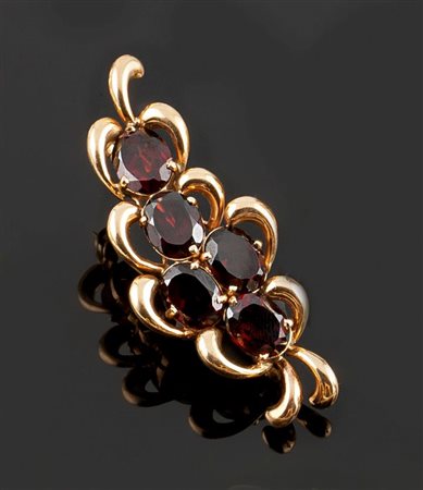 SPILLA Spilla in oro giallo, a volute vegetali, con al centro cinque granati...