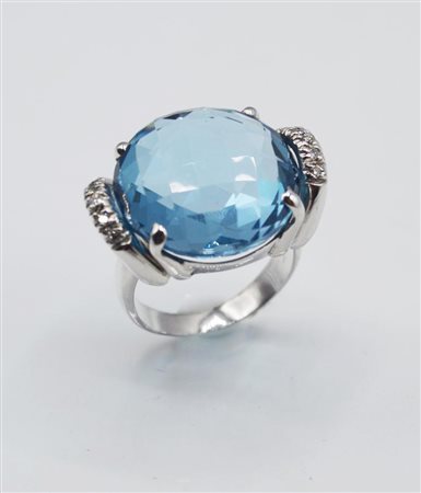 ANELLO IN ORO BIANCO, TOPAZIO E DIAMANTI decorato al centro da un topazio blu...
