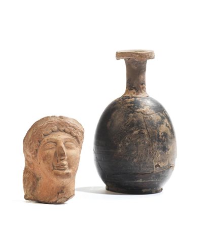 UNGUENTARIO A BOTTIGLIA E TESTINA VOTIVA FEMMINILE Unguentario a bottiglia a...