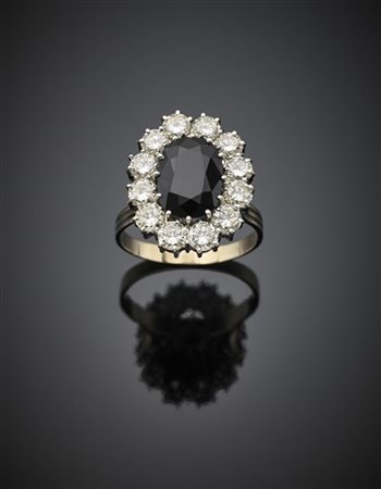 Anello in oro bianco con zaffiro ovale di ct. 7 circa e diamanti rotondi per co