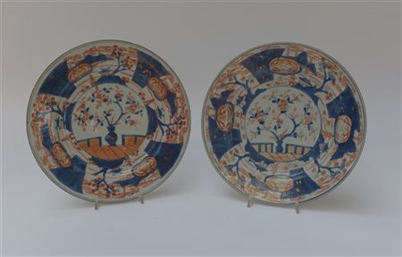 Coppia di piatti in porcellana Imari decorati con motivi floreali e paesaggi (d