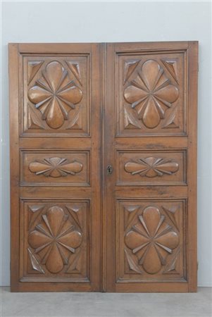 Porta a due ante in noce decorate a riquadri e pannelli quadrilobati scolpiti.