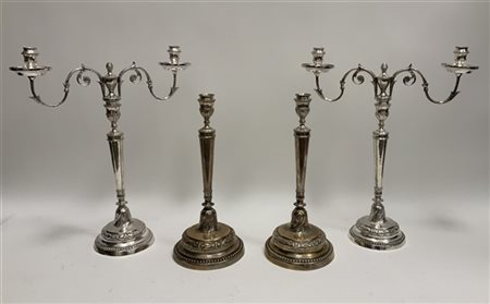 Gruppo di quattro candelieri in metallo argentato due con portacandele sagomati