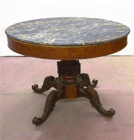 Tavolo tondo con fascia radicata, gamba centrale intagliata terminante a quattr