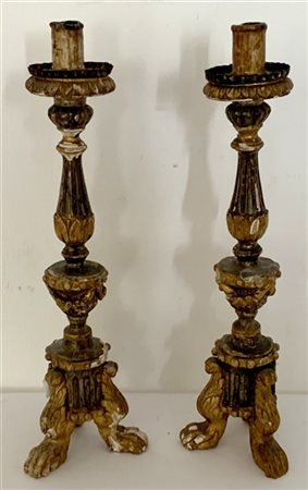 Coppia di candelieri in legno intagliato e dorato, terminanti a piedi ferini. S