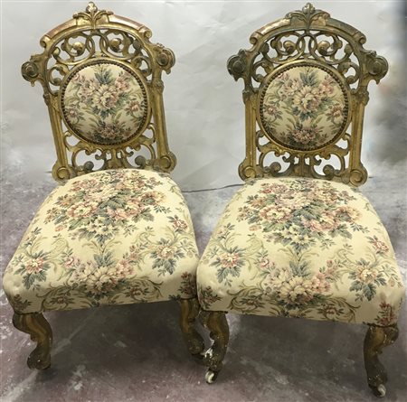 Coppia di sedie basse in legno dorato intagliato traforato a volute e foglie. G