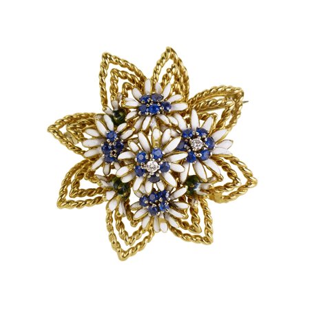 SPILLA IN ORO GIALLO, DIAMANTI E ZAFFIRI realizzata con un motivo floreale...