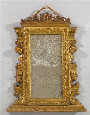 Specchio con cornice in legno dorato finemente scolpito a volute e teste di...