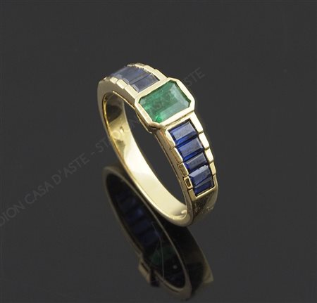 Anello in oro giallo con smeraldo centrale naturale e ai lati zaffiri...