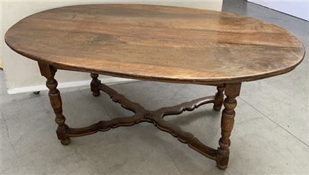 Tavolo da pranzo in noce con piano di forma ovale, gambe a rocchetto riunite da