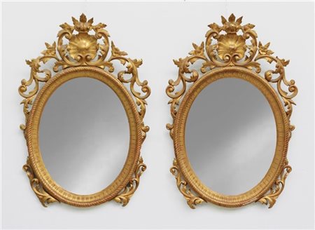 Coppia di specchiere di forma ovale in legno intagliato e dorato con cimasa e f