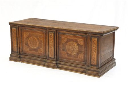 Cassapanca in noce con fronte intarsiato e pannellato a volute fogliate. Secolo