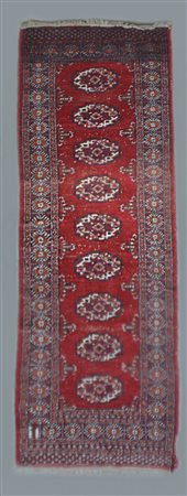 Tappeto passatoia Pakistan, secolo XX. 
Decoro con una fila di Gul su fondo ros