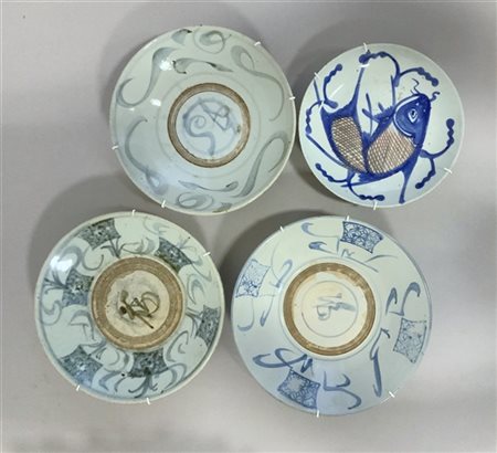 Quattro piatti in porcellana, uno decorato con carpa in blu e rosso, gli altri