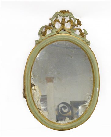 Specchiera di forma ovale in legno laccato verde e oro, cimasa intagliata. Sec.
