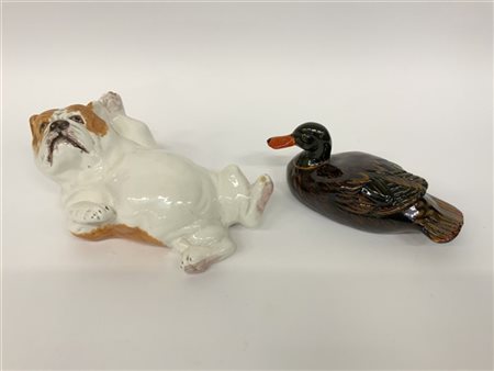 Lotto di due sculture in ceramica dipinta raffiguranti un cane sdraiato e un'an