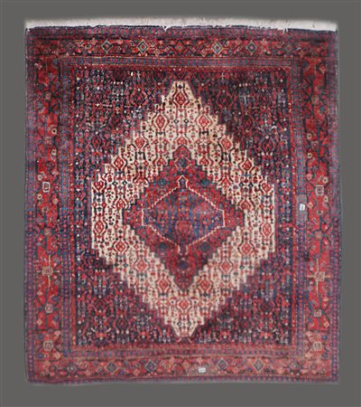 Tappeto Senneh, Persia, 
Decoro con medaglione romboidale rosso su fondo cammel