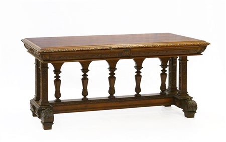 Tavolo neorinascimentale in legno intagliato a volute e motivi fogliati. Gambe