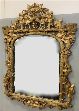 Specchiera in legno intagliato, traforato e dorato, decorata a tralci di vite e