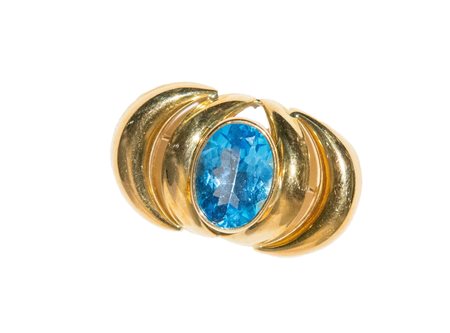 SPILLA CON TOPAZIO AZZURRO OVALE SFACCETTATO Entro montatura in oro giallo...