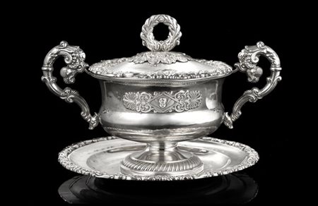 Zuccheriera biansata con piattino in argento. Bordi decorati a volute fogliate,