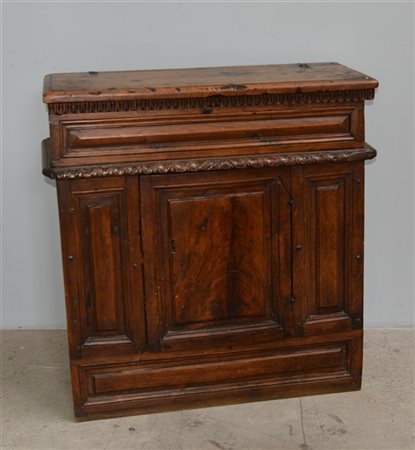 Antico mobiletto in noce con profili intagliati e baccellati. Anta e piano apri