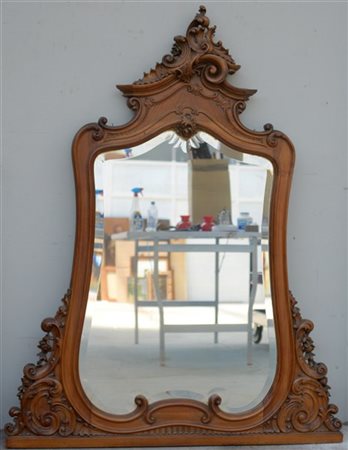 Caminiera sagomata in noce con fregi e cimasa intagliati a volute e motivi vege