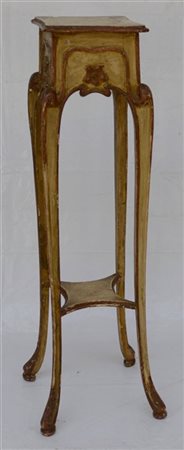 Gueridon di forma mossa in legno intagliato e laccato. Gambe unite da pianetto