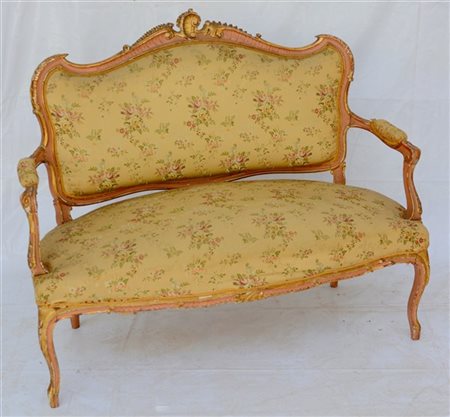 Divano di forma mossa in legno intagliato, laccato e dorato. Schienale sormonta