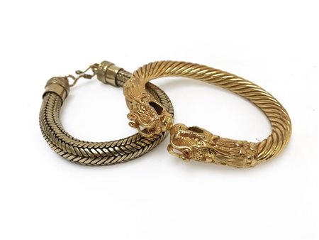 Due bracciali in metallo dorato, uno con motivo a teste di drago, l'altro a mag