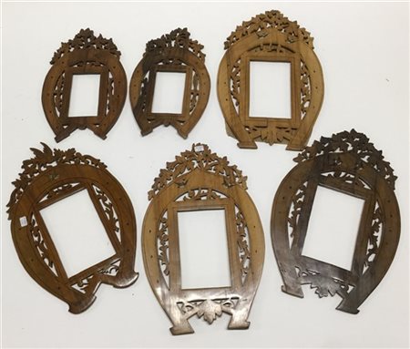 Gruppo di sei cornici in legno intagliato e traforato a forma di ferro di caval