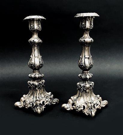 Coppia di candelieri in argento sbalzato a volute e motivi floreali, secolo XIX