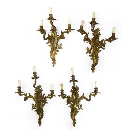 Gruppo di quattro appliques a tre fiamme in bronzo dorato e cesellato a volute