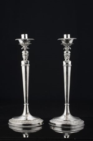 Coppia di candelieri in argento con fusto liscio sormontato da mezzi busti di b