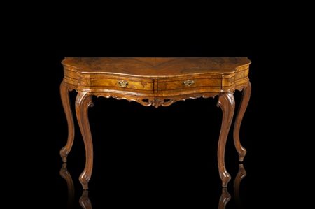 Tavolo da parete di forma mossa lastronato, intagliato e filettato in noce, due