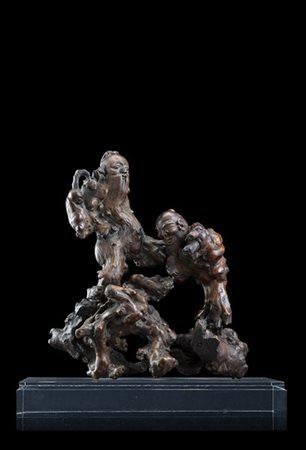 Scultura in radice di legno raffigurante due figure allegoriche su una roccia,