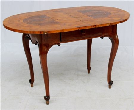 Tavolo con piano di forma ovale intarsiato in legni vari a volute e motivi geom