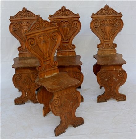 Gruppo di quattro seggiole in legno con schienale e gambe anteriori intagliate