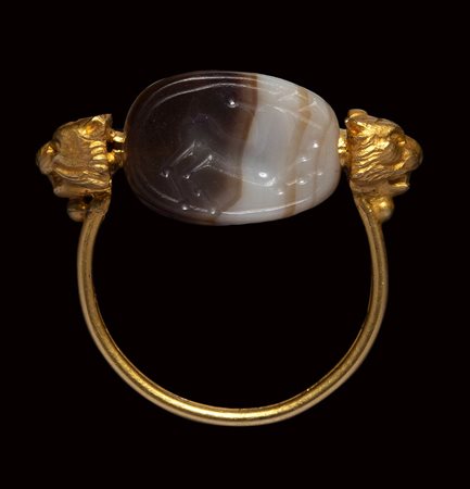 An etruscan banded agate scarab intaglio mounted on an gold ring. Horned stag running.
